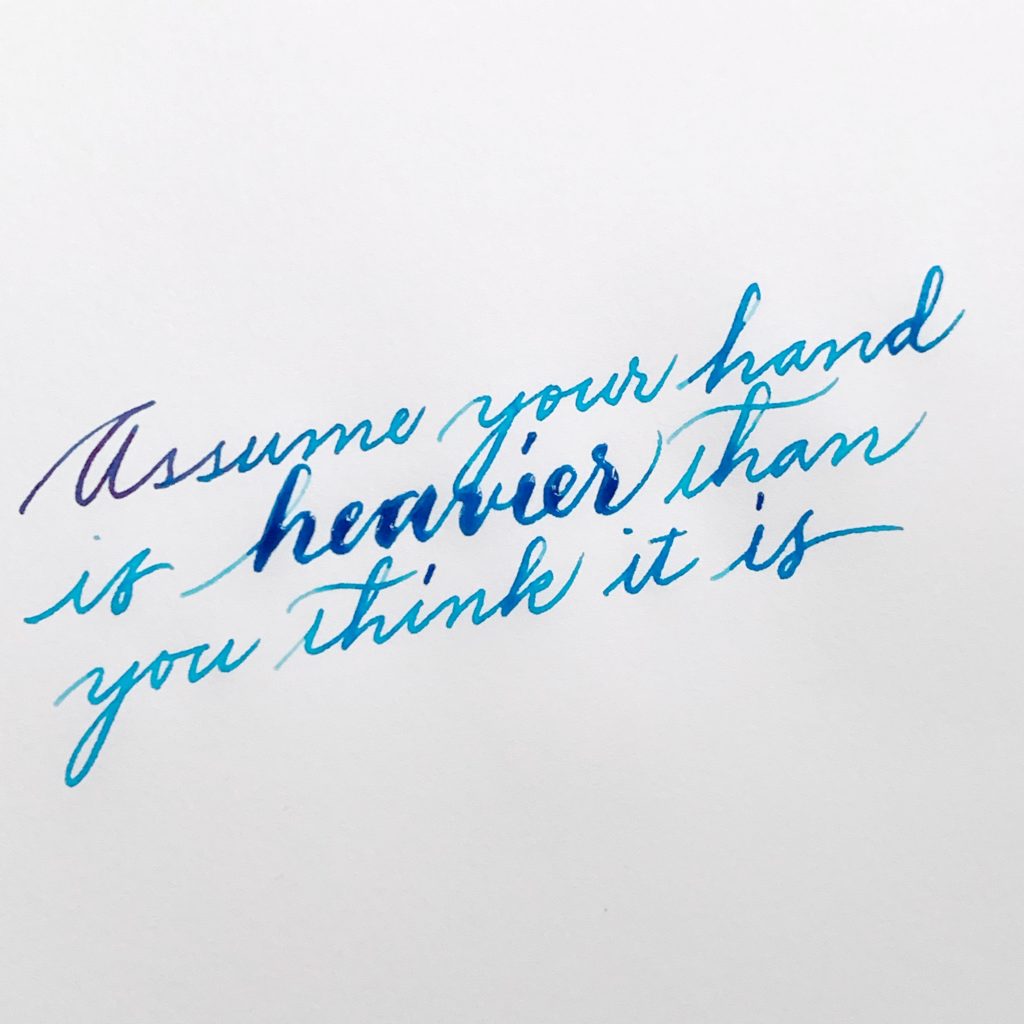 Written in cursive on paper: "Assume your hand is heavier than you think it is"