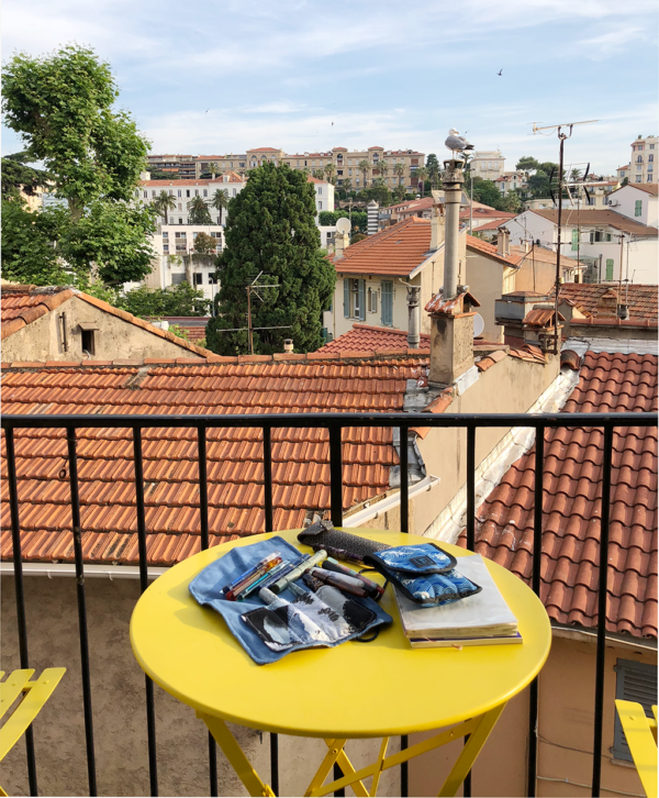 Pens on a yellow table with a view of Cannes